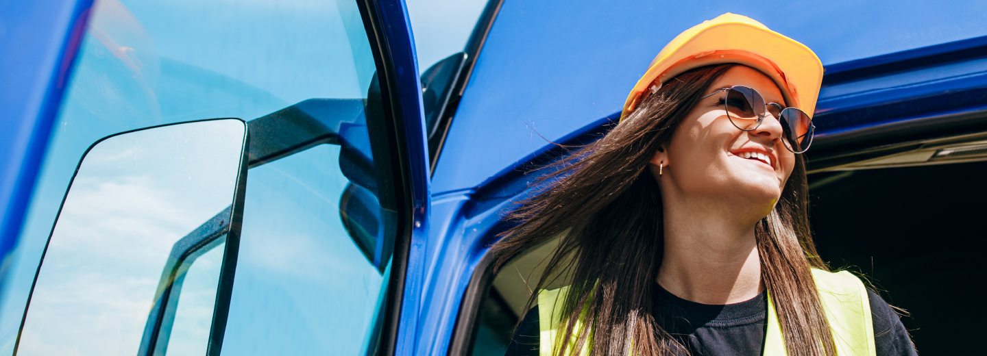 Helmsman Auto - Woman exiting semi truck wearing glasses and hard hat.